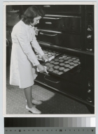 Academics, Food Administration student, Marian Kaufman, removing cookie sheet from oven, 1942.