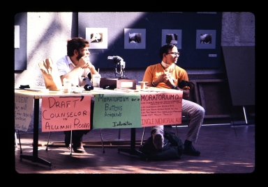 Two unidentified students sit at a table in the Student Alumni Union promoting the Moratorium