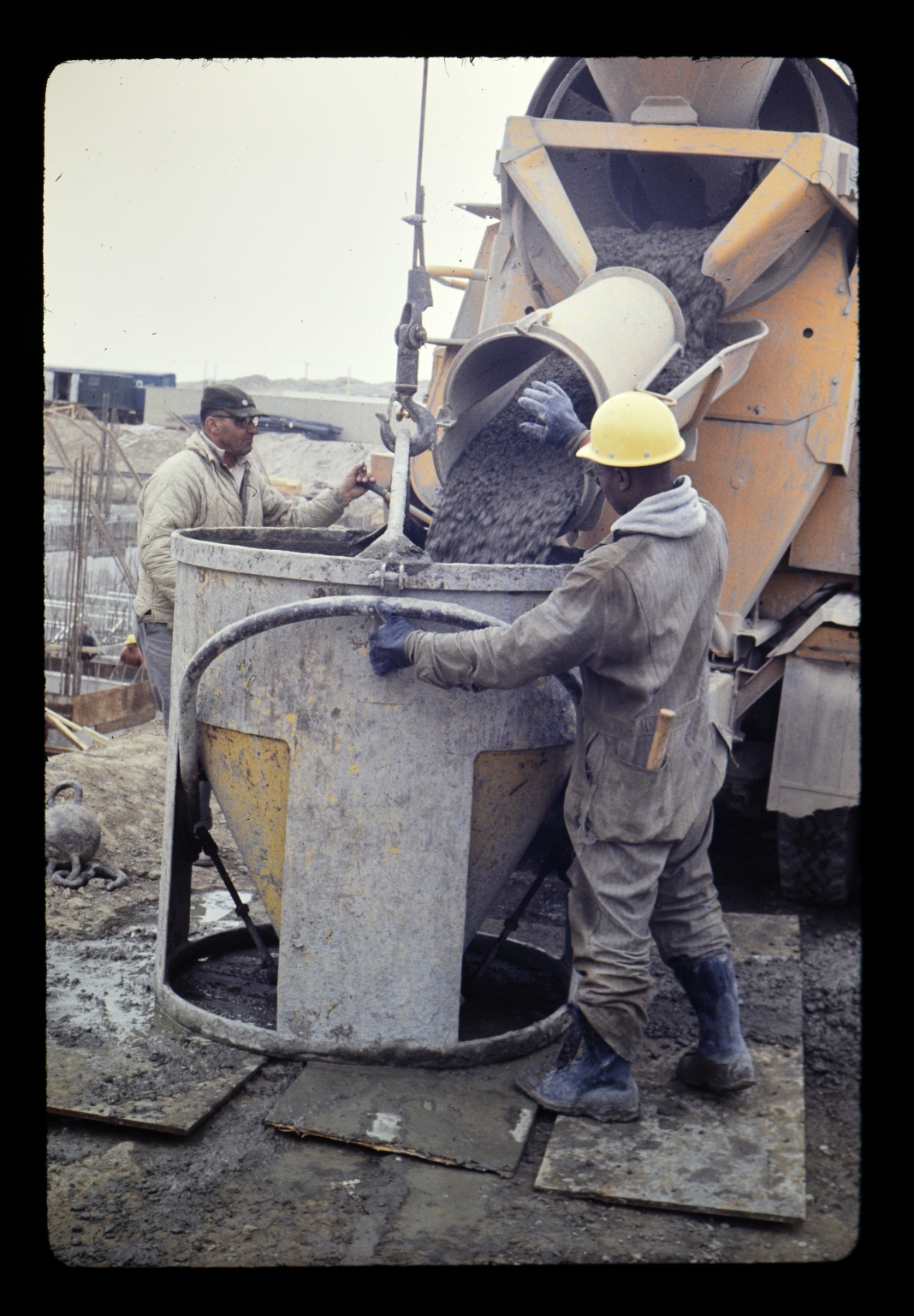 Two construction workers pour cement